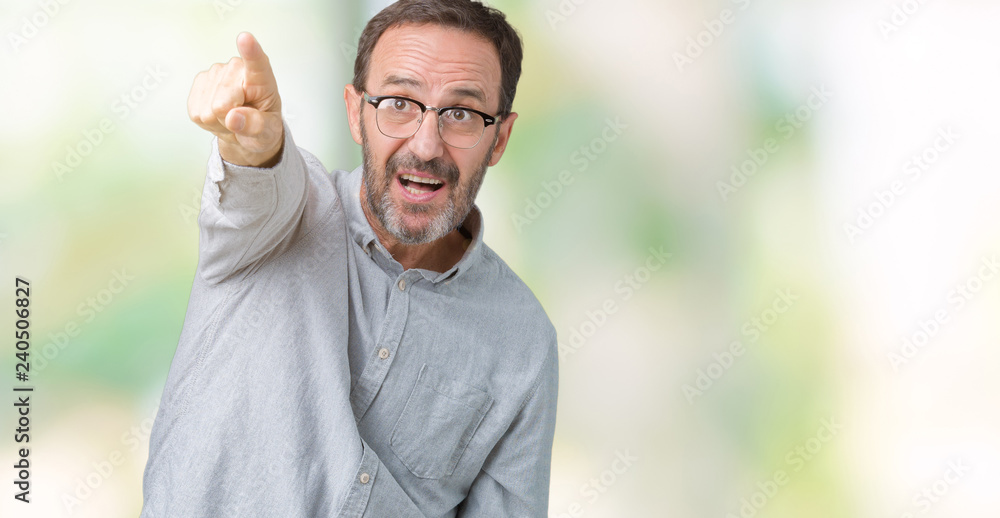Handsome middle age elegant senior man wearing glasses over isolated background Pointing with finger surprised ahead, open mouth amazed expression, something in front Handsome middle age elegant senior man wearing glasses over isolated background Pointing with finger surprised ahead, open mouth amazed expression, something in front