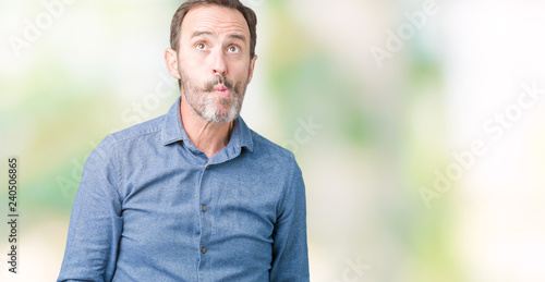 Handsome middle age elegant senior man over isolated background making fish face with lips, crazy and comical gesture. Funny expression.