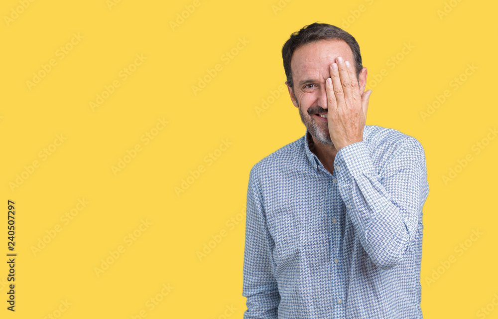 Handsome middle age elegant senior man over isolated background covering one eye with hand with confident smile on face and surprise emotion. Handsome middle age elegant senior man over isolated background covering one eye with hand with confident smile on face and surprise emotion.