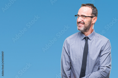 Middle age hoary senior business man wearing glasses over isolated background looking away to side with smile on face, natural expression. Laughing confident.