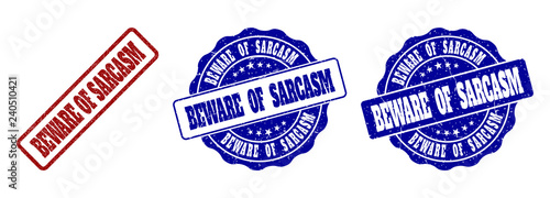 BEWARE OF SARCASM grunge stamp seals in red and blue colors. Vector BEWARE OF SARCASM labels with scratced style. Graphic elements are rounded rectangles, rosettes, circles and text labels.