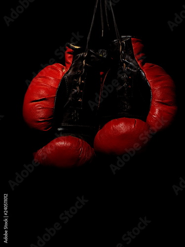 Old leather red boxing gloves hanging in the dark © Oleksii