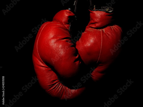 Old leather red boxing gloves hanging in the dark