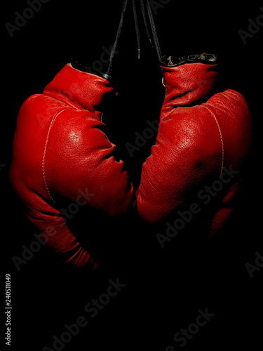Old leather red boxing gloves hanging in the dark © Oleksii