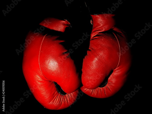 Old leather red boxing gloves hanging in the dark
