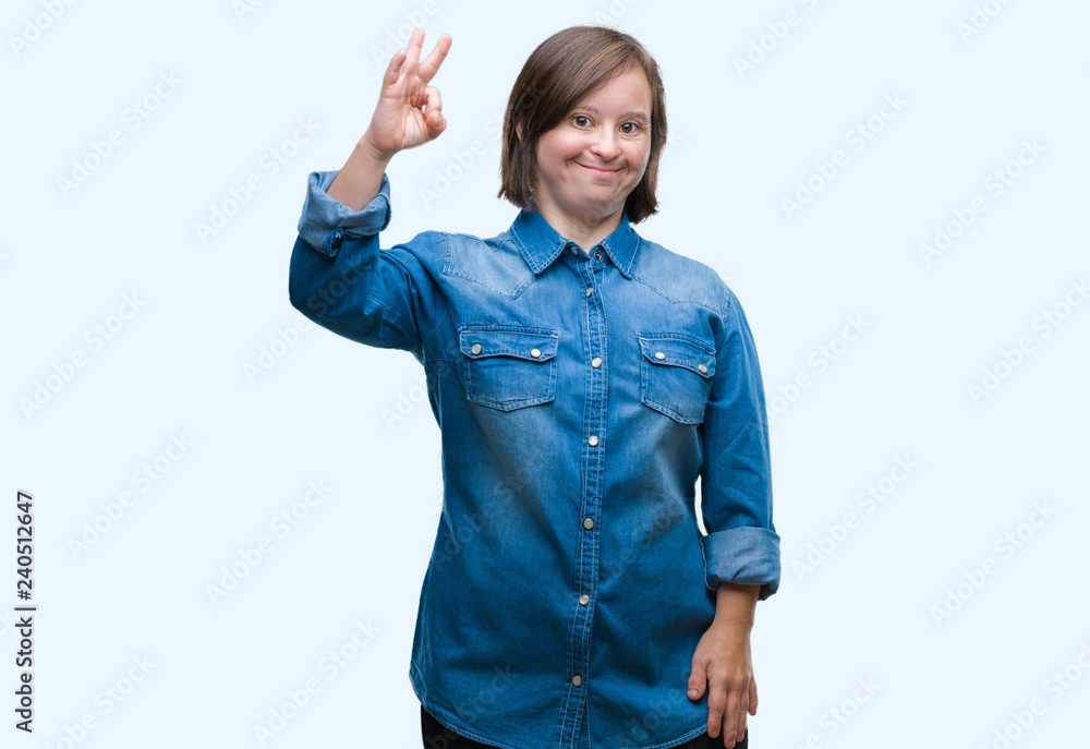 Young adult woman with down syndrome over isolated background smiling positive doing ok sign with hand and fingers. Successful expression. Young adult woman with down syndrome over isolated background smiling positive doing ok sign with hand and fingers. Successful expression.