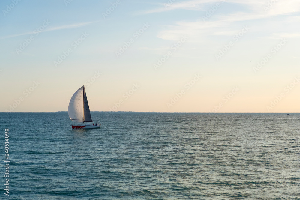 Sailing boat on open sea at sunset. Granville. Normandy, France.