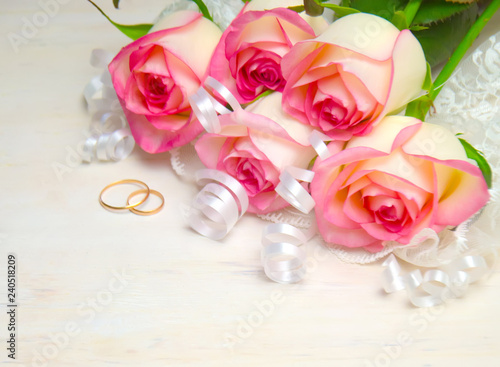 pink rose ribbon and wedding rings on wood white