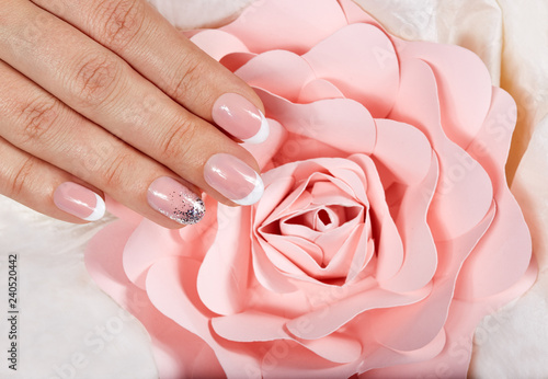 Hand with artificial french manicured nails and pink rose flower