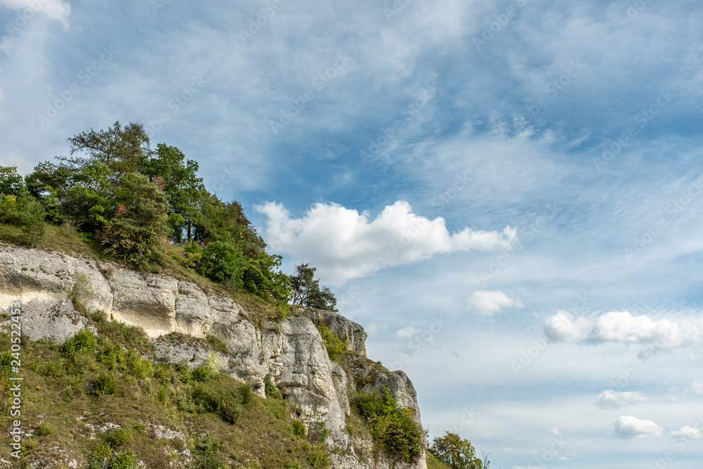 Naklejka premium Bewaldete Felswand mit Wolkenhimmel auf der schwäbischen Alb