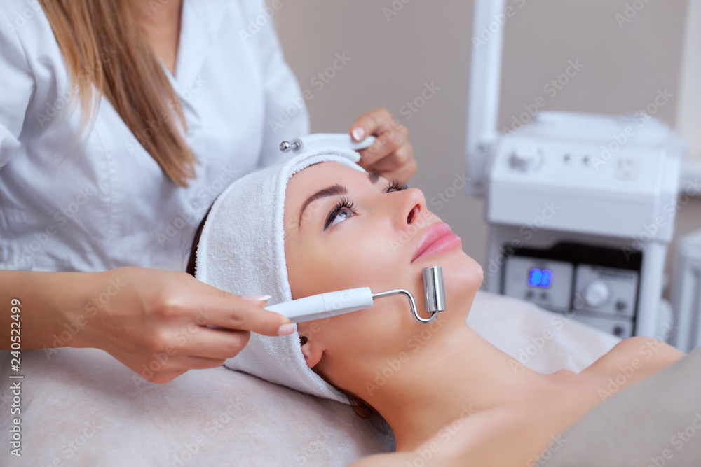 The cosmetologist makes the apparatus a procedure of Microcurrent therapy of a beautiful, young woman in a beauty salon. Cosmetology and professional skin care. The cosmetologist makes the apparatus a procedure of Microcurrent therapy of a beautiful, young woman in a beauty salon. Cosmetology and professional skin care.