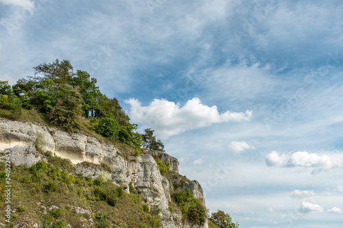 Bewaldete Felswand mit Wolkenhimmel auf der schwäbischen Alb