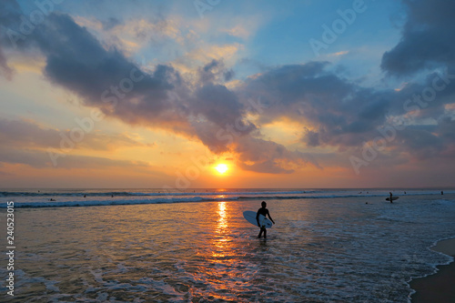 Young surfer silhouette with surfboard at beautiful sunset background, Kuta beach, Bali, Indonesia © art_of_sun
