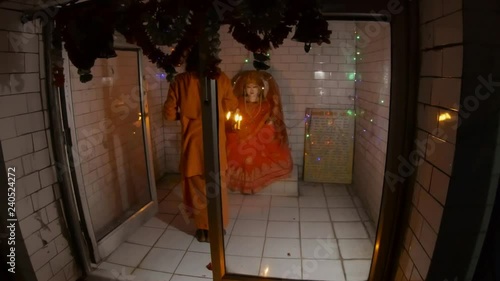 Hindu monk performs night religious ritual aarti with fire in front of statue of Goddess flashlights photo