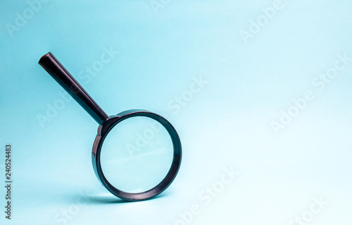 Magnifying glass on blue background. Concept of search and analysis, analytics and study of details. Validation, identification of fakes and crimes, review and study of the world.