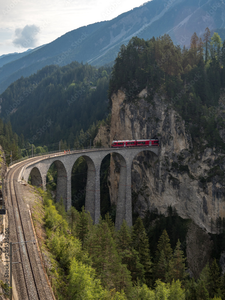 Red train on famous Landwasser Viaduct bridge.The Rhaetian Railway section from the Albula/Bernina area (the part from Thusis to Tirano, including St Moritz), Switzerland, Europe. August, 2018 Red train on famous Landwasser Viaduct bridge.The Rhaetian Railway section from the Albula/Bernina area (the part from Thusis to Tirano, including St Moritz), Switzerland, Europe. August, 2018