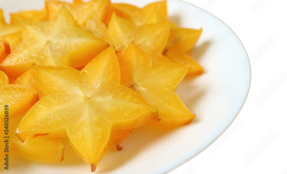 Vibrant orange yellow fresh ripe Star Fruit sliced in pieces served on white plate isolated on white background Vibrant orange yellow fresh ripe Star Fruit sliced in pieces served on white plate isolated on white background