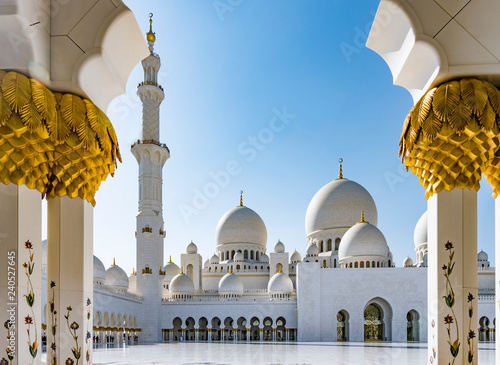 Photography Sheikh Zayed Grand Mosque in Abu Dhabi seen between gold and marble pillars