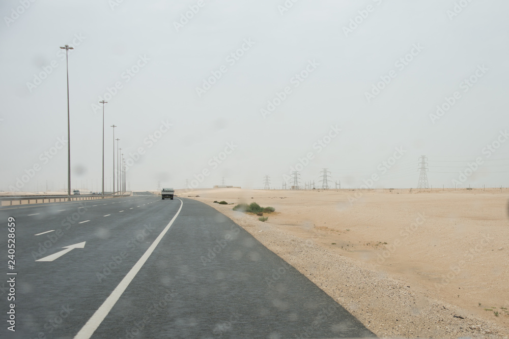 Fototapeta premium Desert highway in Qatar with raindrops on car window