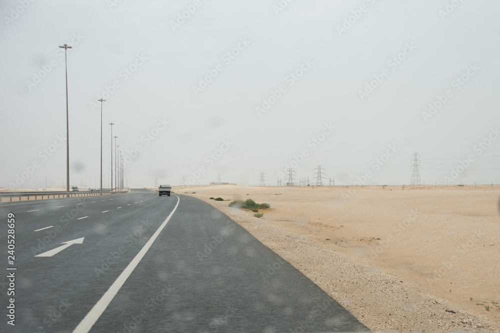 Desert highway in Qatar with raindrops on car window