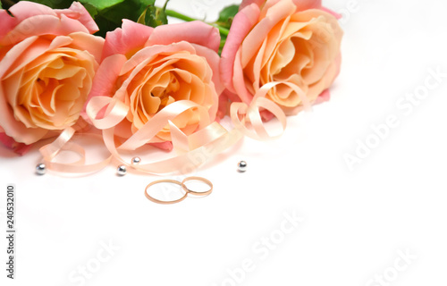 delicate roses and ribbons and beads and wedding rings on wooden white background selective focus