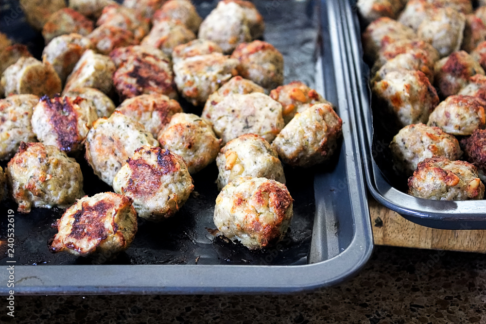 Freshly baked meatballs about to be taken off a cookie sheet