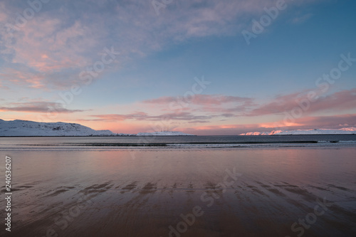 Landscape with a winter beach on the shore of the Barents Sea on the Kola Peninsula at sunset