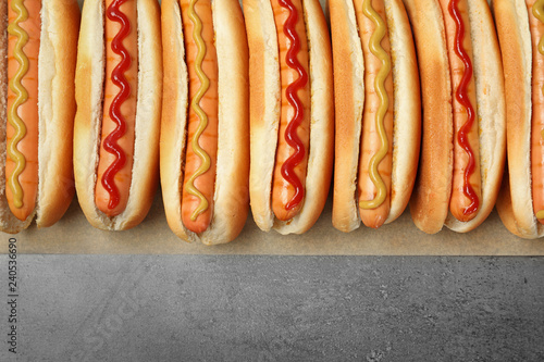 Tasty fresh hot dogs on grey background, top view