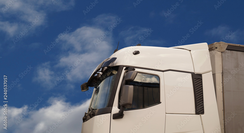 Closeup of a truck cabin against a sky covered with clouds.
