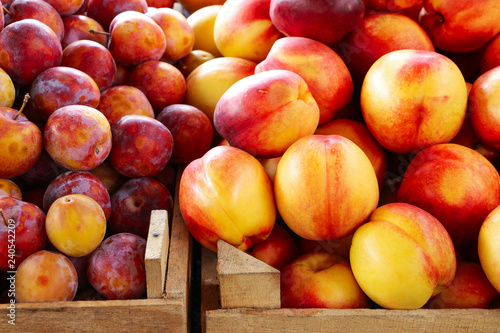 Ripe plums and nectarines in wooden boxes on the market counter. Close-up.