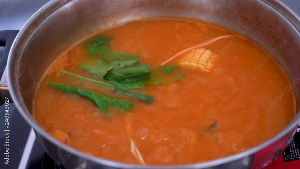 Woman hand puts vegetables ingredient on hot Tom Yum soup in a pan. Shot in 4k resolution Woman hand puts vegetables ingredient on hot Tom Yum soup in a pan. Shot in 4k resolution