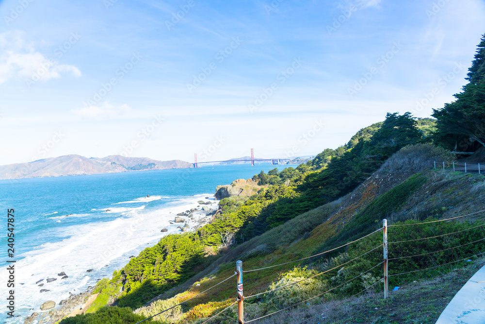 The view of golden gate bridge in Lands end at San Francisco- San Francisco. summer , cloud , rock , sea, plant.