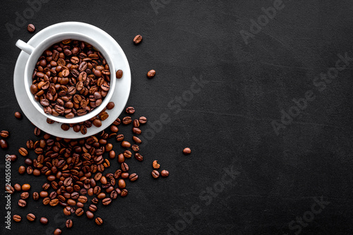 Brown roasted coffee beans scattered on black background top view mockup