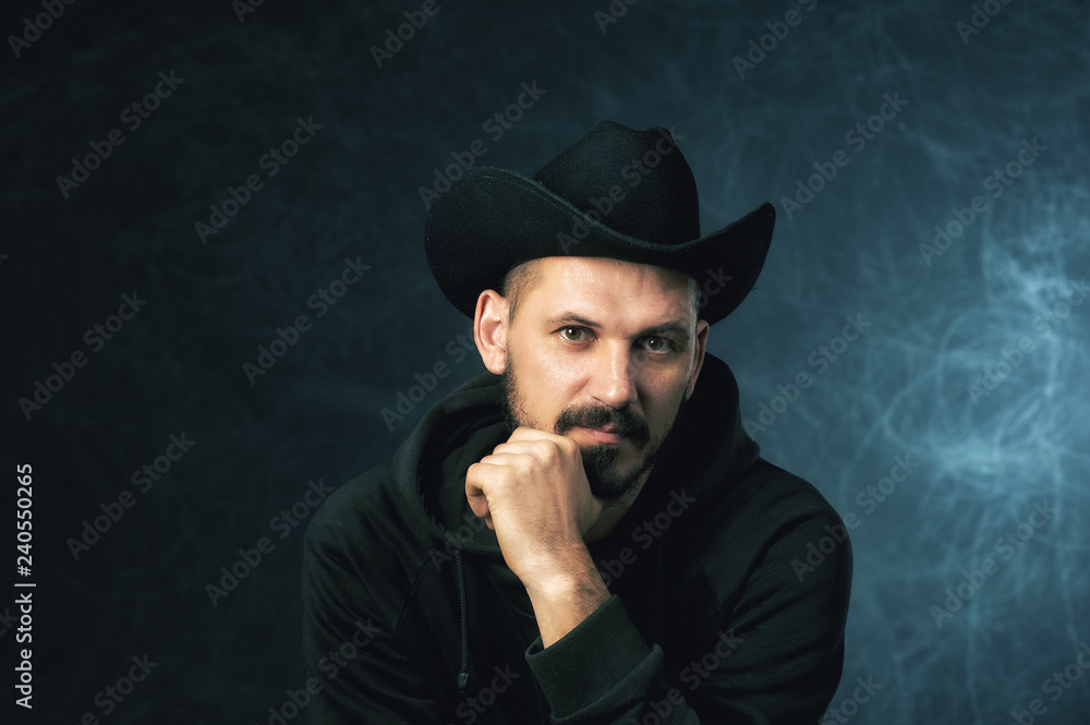 Studio portrait of a man in a wide-brimmed hat on a dark background Studio portrait of a man in a wide-brimmed hat on a dark background