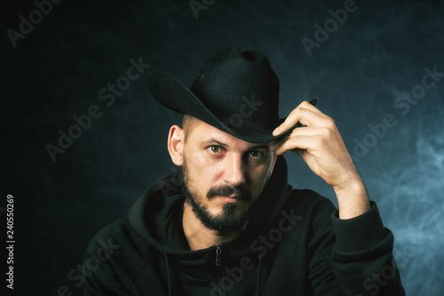 Studio portrait of a man in a wide-brimmed hat on a dark background © fisher05