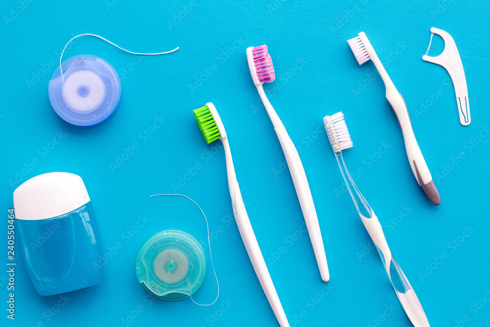 Tooth care with toothbrush, dental floss and dentist instruments. Set of cleaning products for teeth on blue background top view