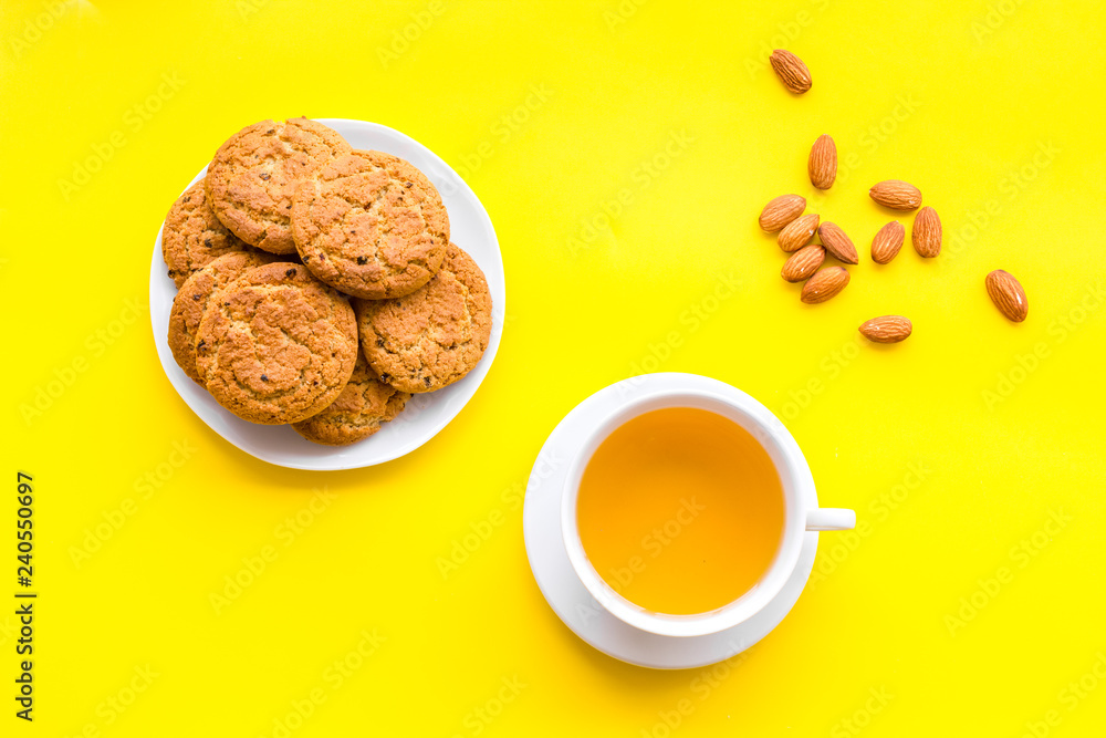 Dessert for evening tea. Cup of tea, fresh homemade cookies on yellow background top view Dessert for evening tea. Cup of tea, fresh homemade cookies on yellow background top view