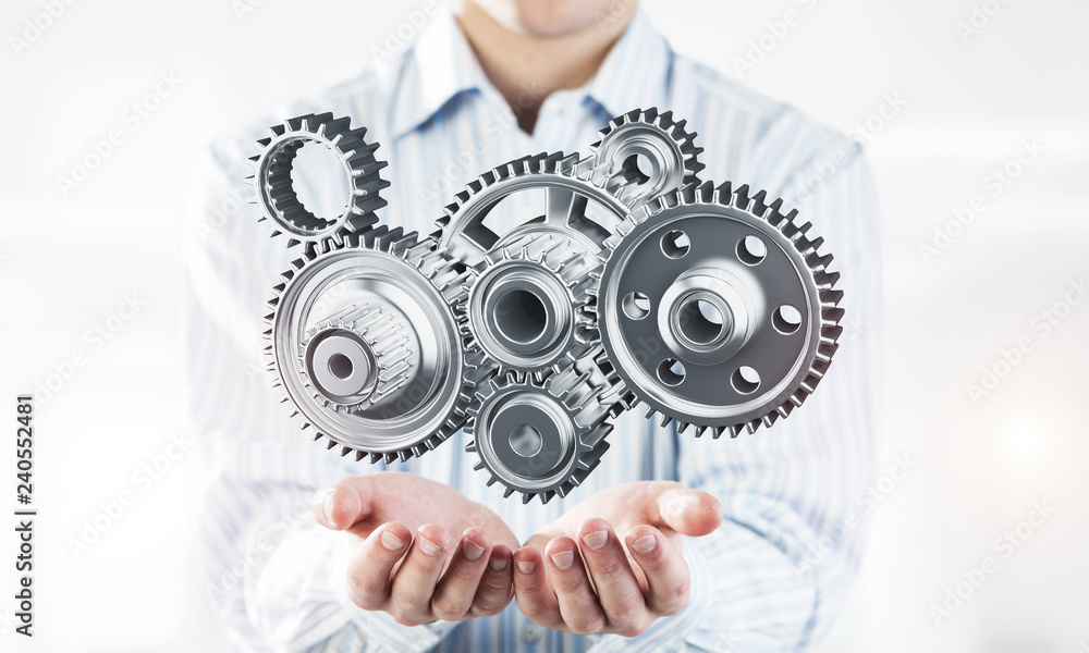 Engine mechanism in male ahnds as symbol for cooperation or team Engine mechanism in male ahnds as symbol for cooperation or team