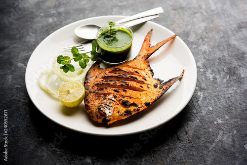 Tandoori Pomfret fish cooked in a clay oven and garnished with lemon , mint, cabbage and carrot salad. Selective focus photo