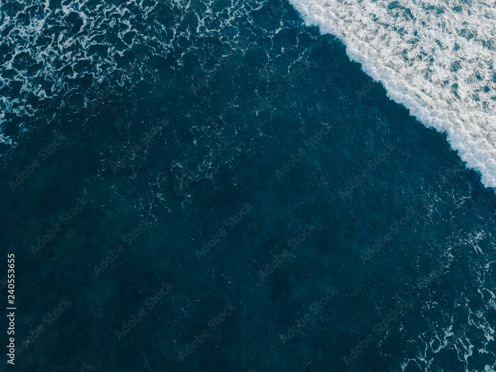 Fototapeta premium Sea aerial view, top view, amazing nature background. Blue of the water and beautiful sand coasline. Azure beach with turquoise waves and clear water of ocean at sunny day. Sea view from flying drone