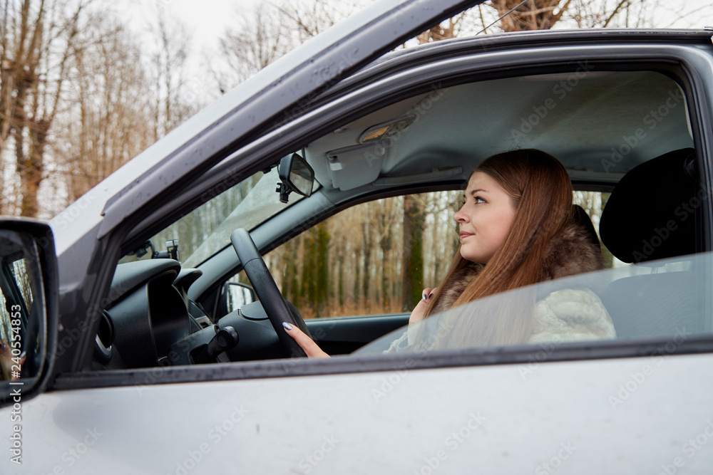 Beautiful young sexy woman in car looking from window and autumn forest ackground