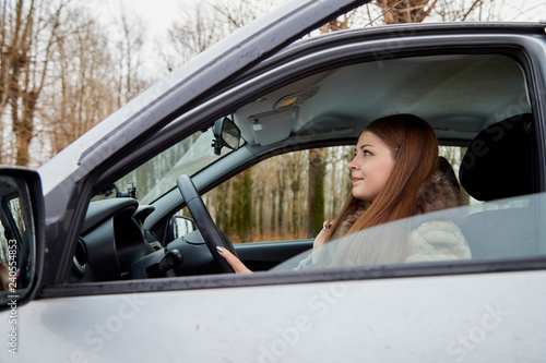 Beautiful young sexy woman in car looking from window and autumn forest ackground