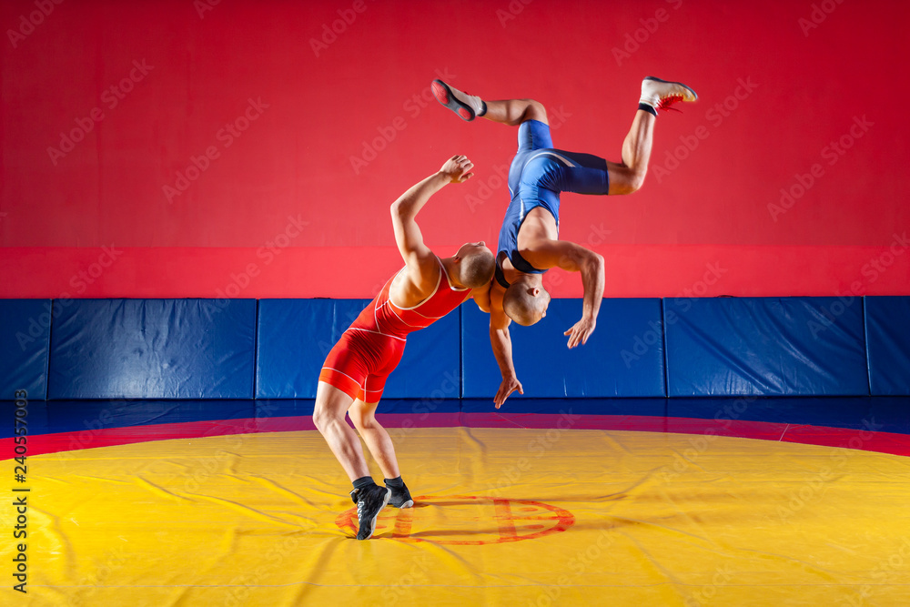 Two strong wrestlers in medical masks and wrestling tights are wrestlng on  a yellow wrestling carpet in the gym. Young man doing grapple.Sports con  Stock Photo - Alamy