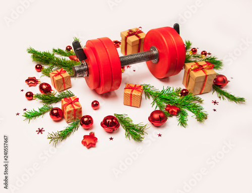 Christmas or New Year on a white background. Composition with dumbbells, gift, red and gold glass balls, fir tree branches for healthy lifestyle and sport