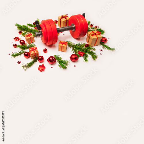 Christmas or New Year on a white background. Composition with dumbbells, gift, red and gold glass balls, fir tree branches for healthy lifestyle and sport