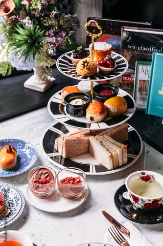 Tableau sur toile English afternoon tea set including hot tea, pastry, scones, sandwiches and mini pies on marble top table
