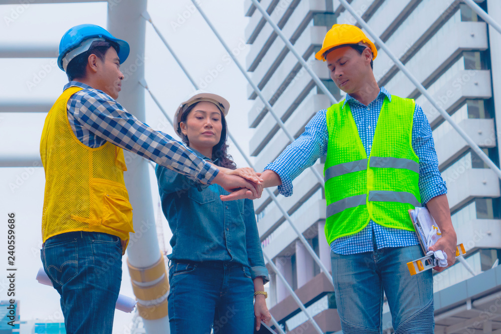 Working engineer. They are join hands mean teamwork and spirit beside building background. Photo concept for engineering and team work. Working engineer. They are join hands mean teamwork and spirit beside building background. Photo concept for engineering and team work.