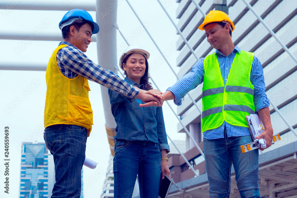 Working engineer. They are join hands mean teamwork and spirit beside building background. Photo concept for engineering and team work. Working engineer. They are join hands mean teamwork and spirit beside building background. Photo concept for engineering and team work.