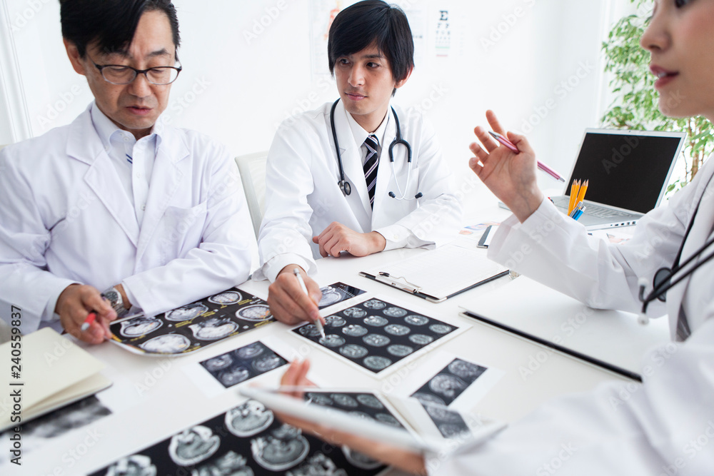 レントゲン写真やパソコン、タブレットのある医師の会議シーン