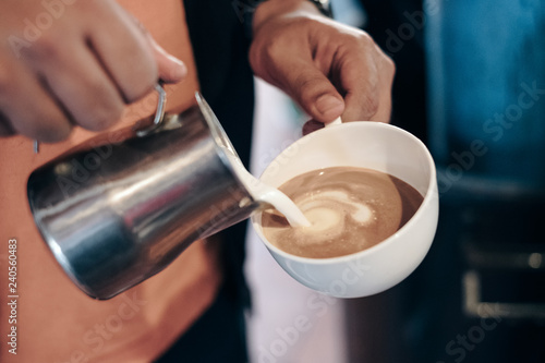 Barista pouring milk on coffee cup making heart